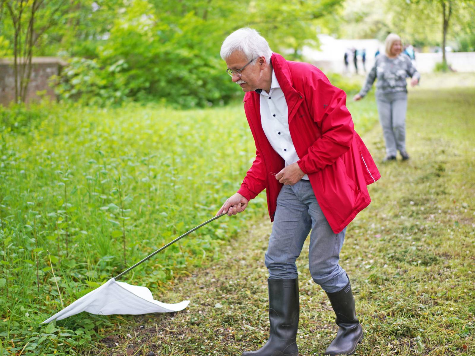 Ein Mann streift mit einem Tuch durch hohes Gras.