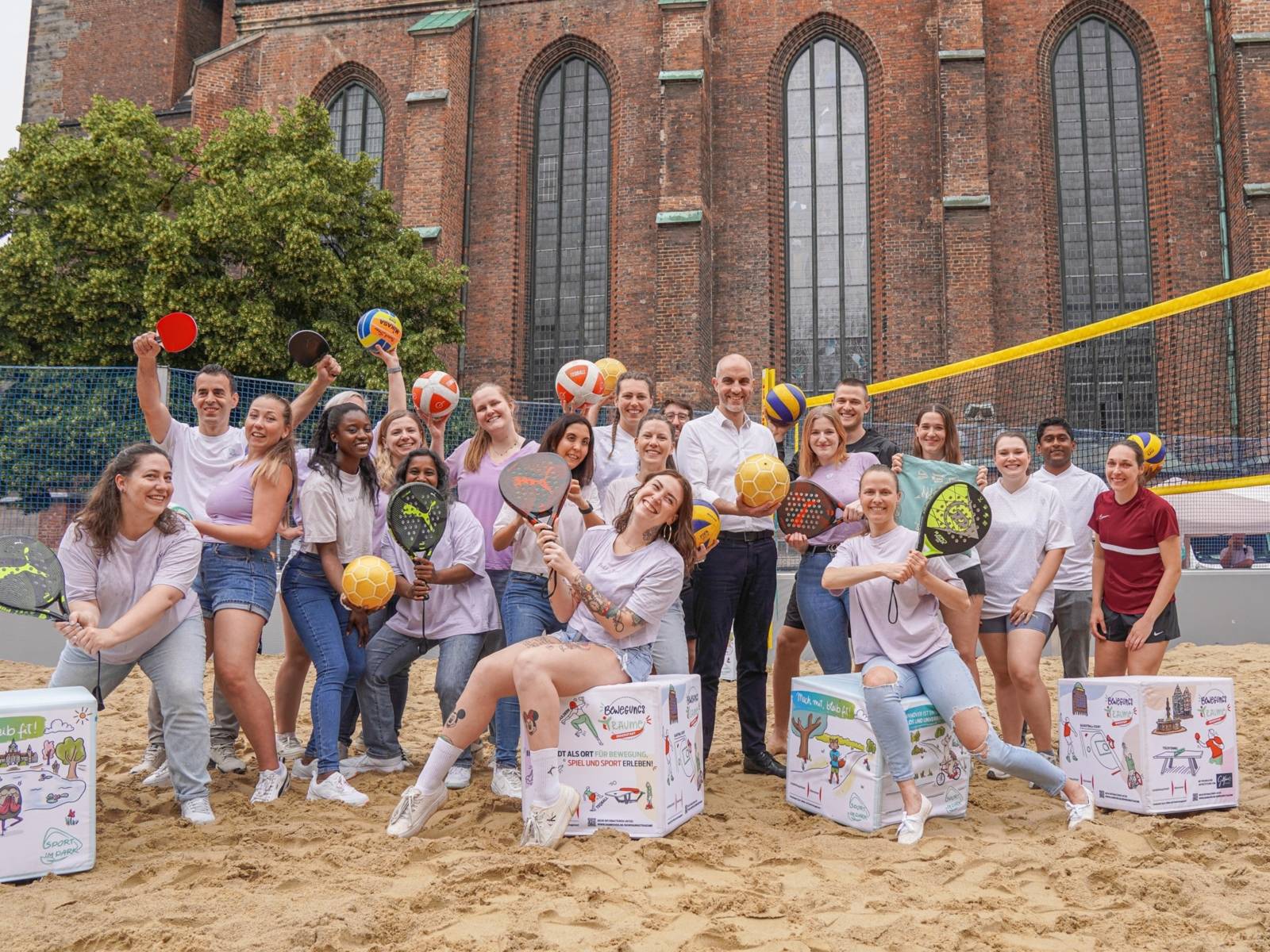 Eine Gruppe von Menschen auf einem Beachvolleyball-Feld.