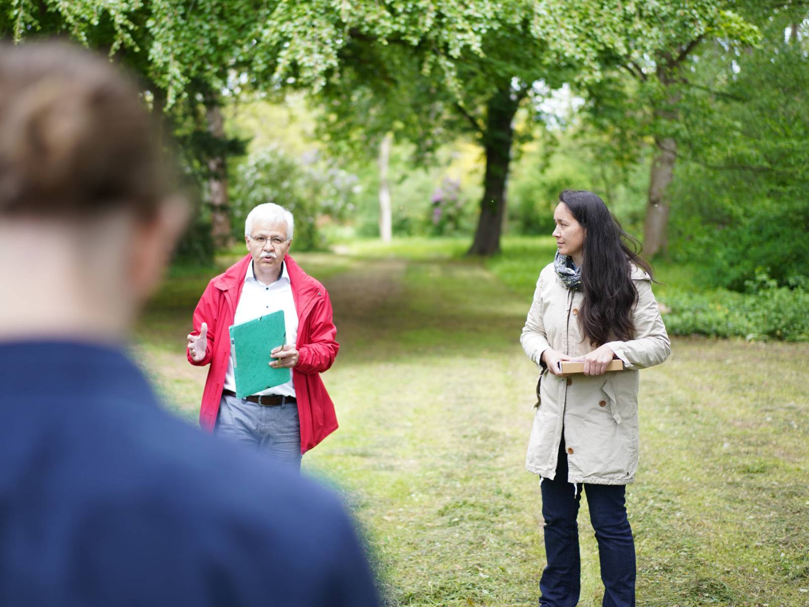 Personen stehen in einem Park und erklären etwas.