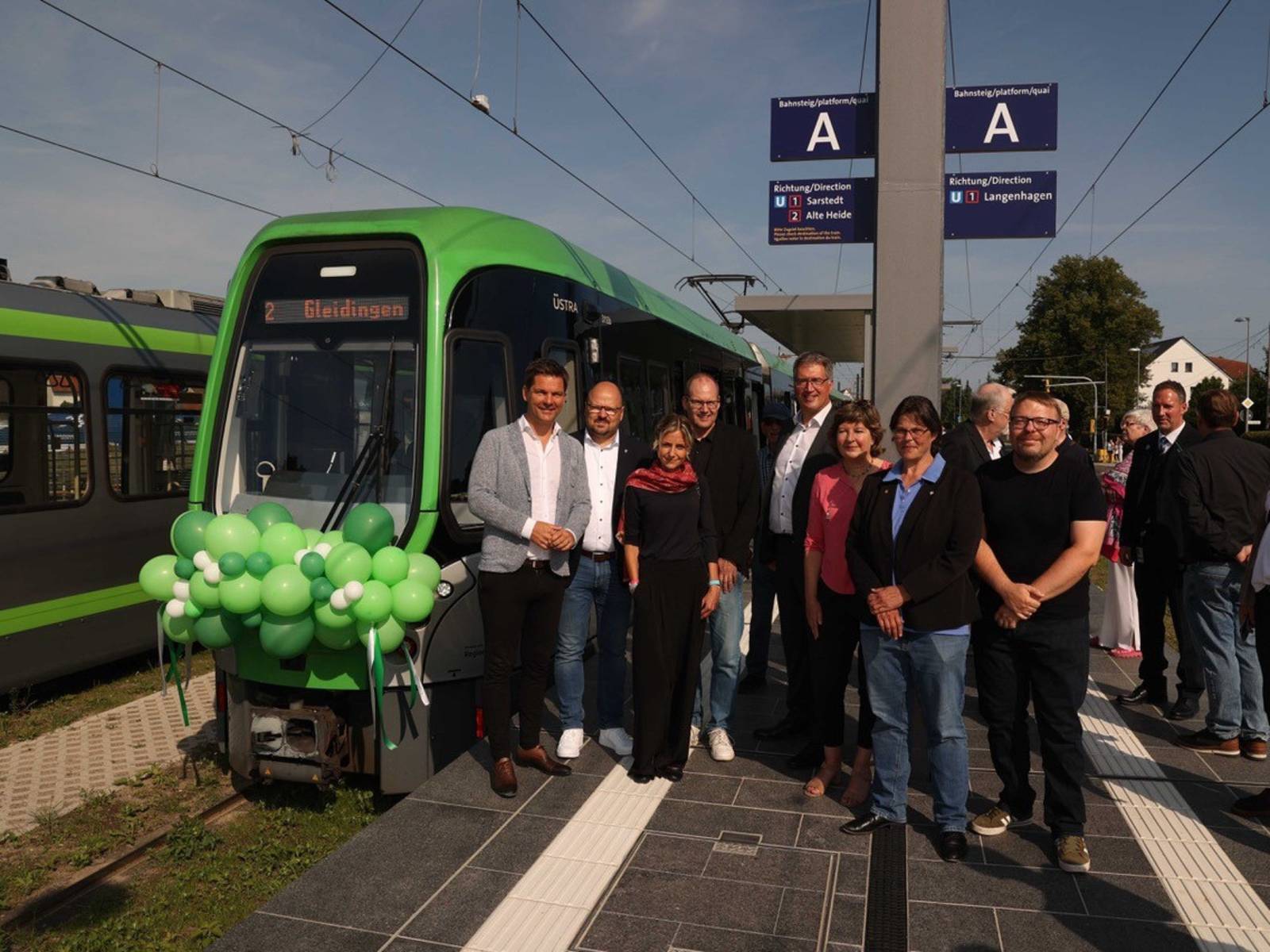 Eine Gruppe von Menschen mit einer Straßenbahn mit Luftballons am Triebwagen