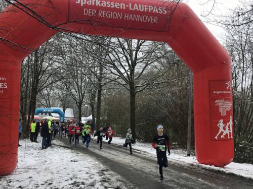 Läufergruppe an einem aufblasbaren Start-Tor im Schnee.