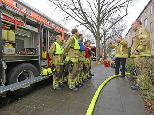 Auszubildende Feuerwehrmänner stehen vor einem Fahrzeug