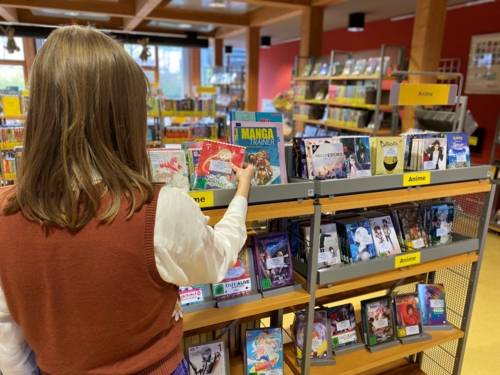 Mädchen betrachtet Animeabteilung der Stadtbibliothek