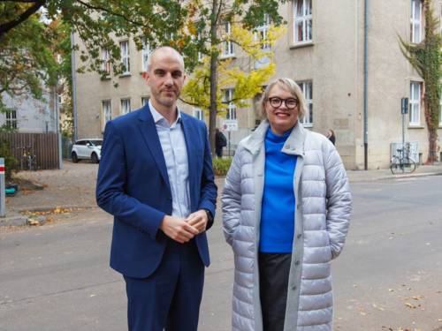 Zwei Personen vor einem Gebäude.