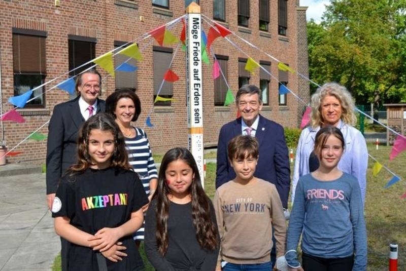 Erwachsene und Kinder vor einem so genannten Friedenspfahl (Holzpfahl)