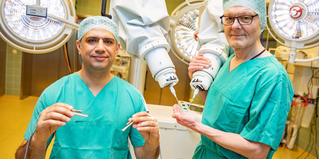 Zwei Männer in medizinischer Kleidung mit OP-Roboter.