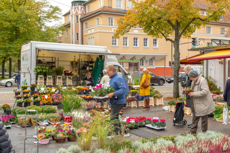 Blumen werden den Marktbesuchenden angeboten.