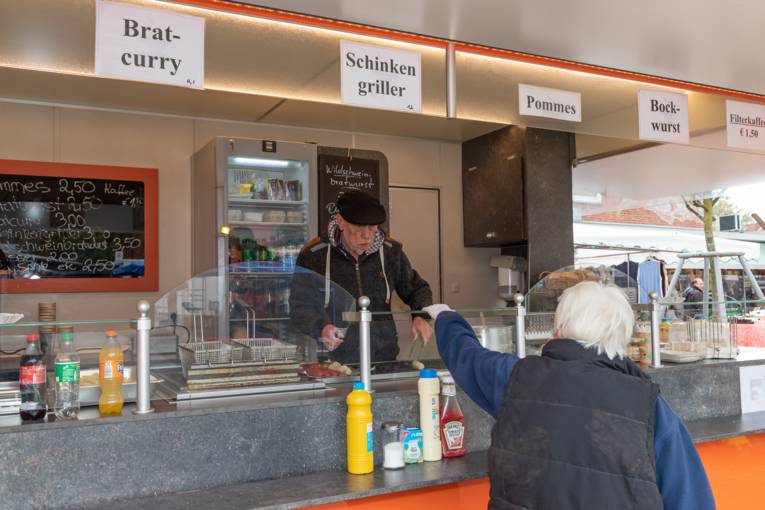 Eine Kundin kauft Bratwurst an einem Stand.